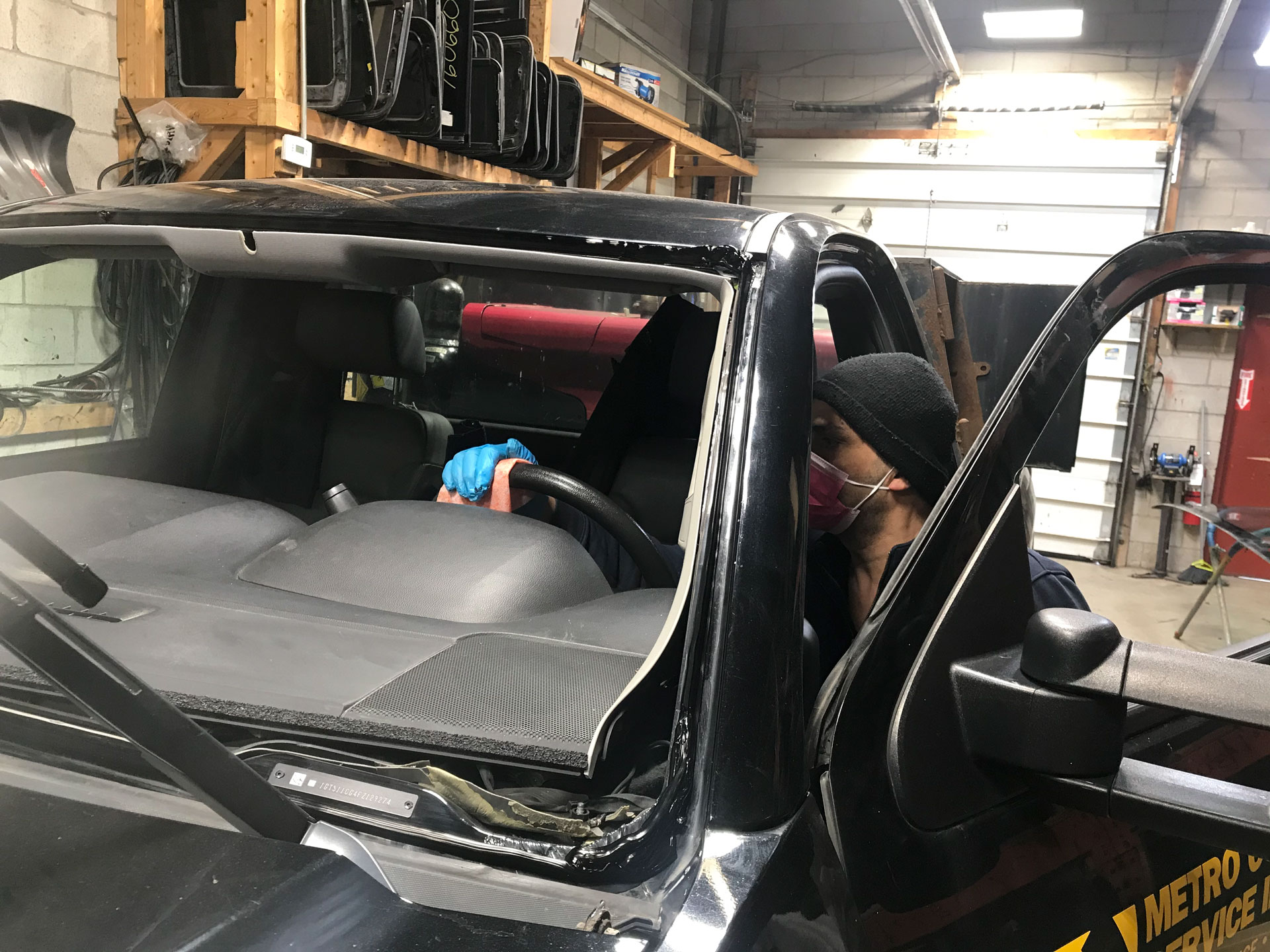 Dixie Auto Glass tecnician wipping down the truck steering wheel of customers car with lysol to prevent coronavirus COVID 19 at the shop after the windshield replacement work